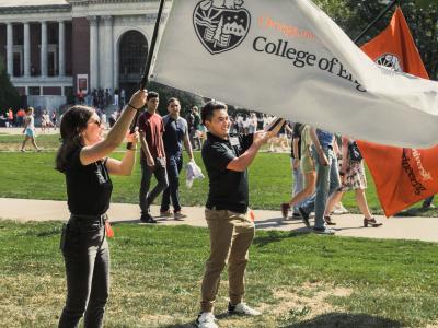 Two students wave College of Engineering flags at convocation.